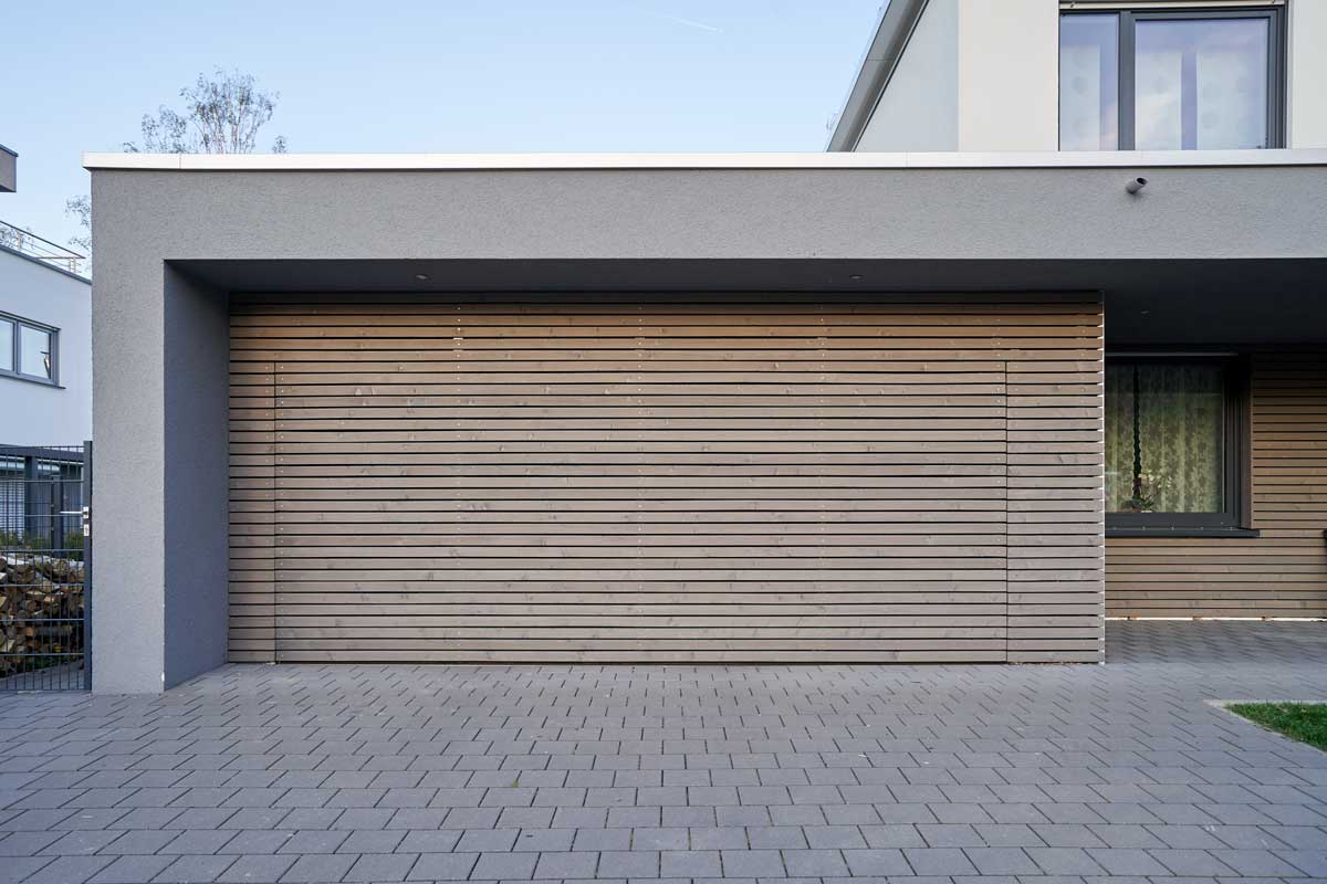 A modern Scandinavian-style garage with a wood-paneled garage door.